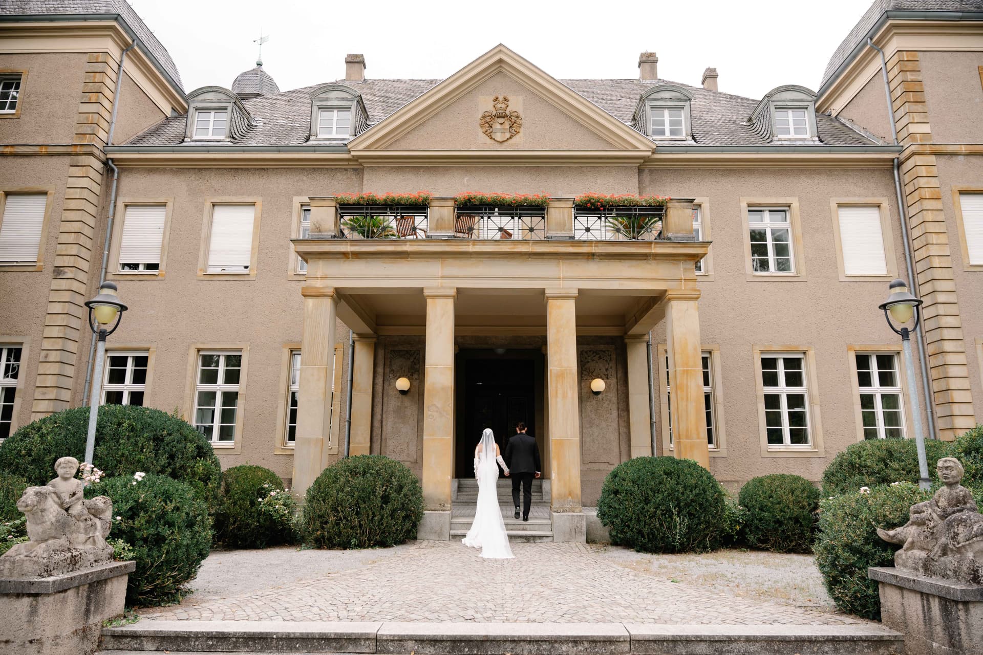 Brautpaar vor elegant klassischem Herrenhaus mit Säulen